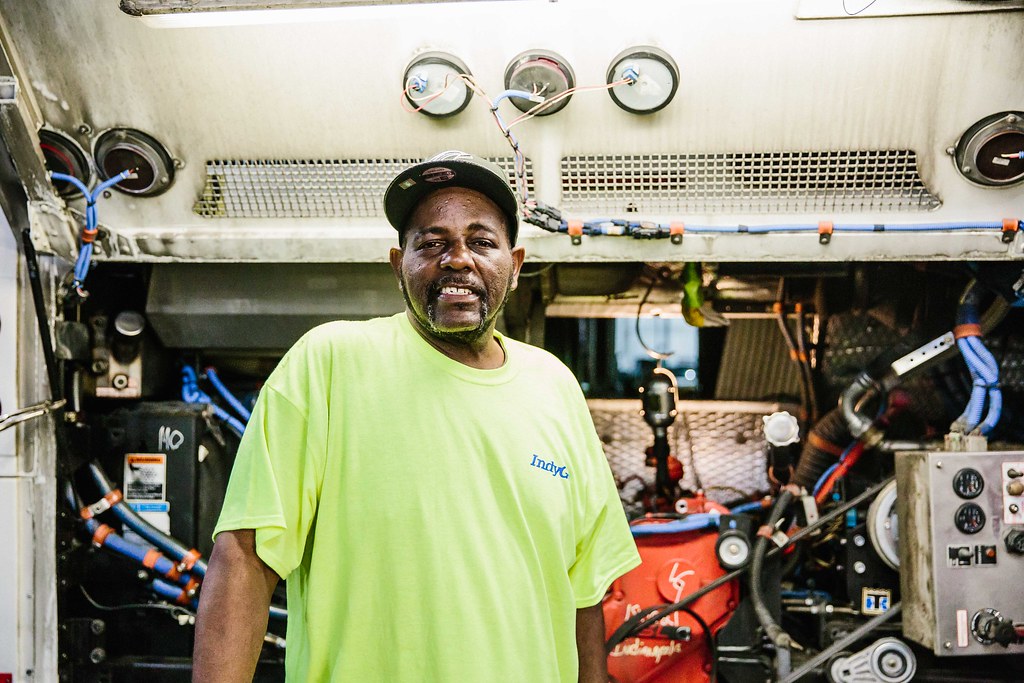 IndyGo mechanic smiling at camera while working on a bus engine
